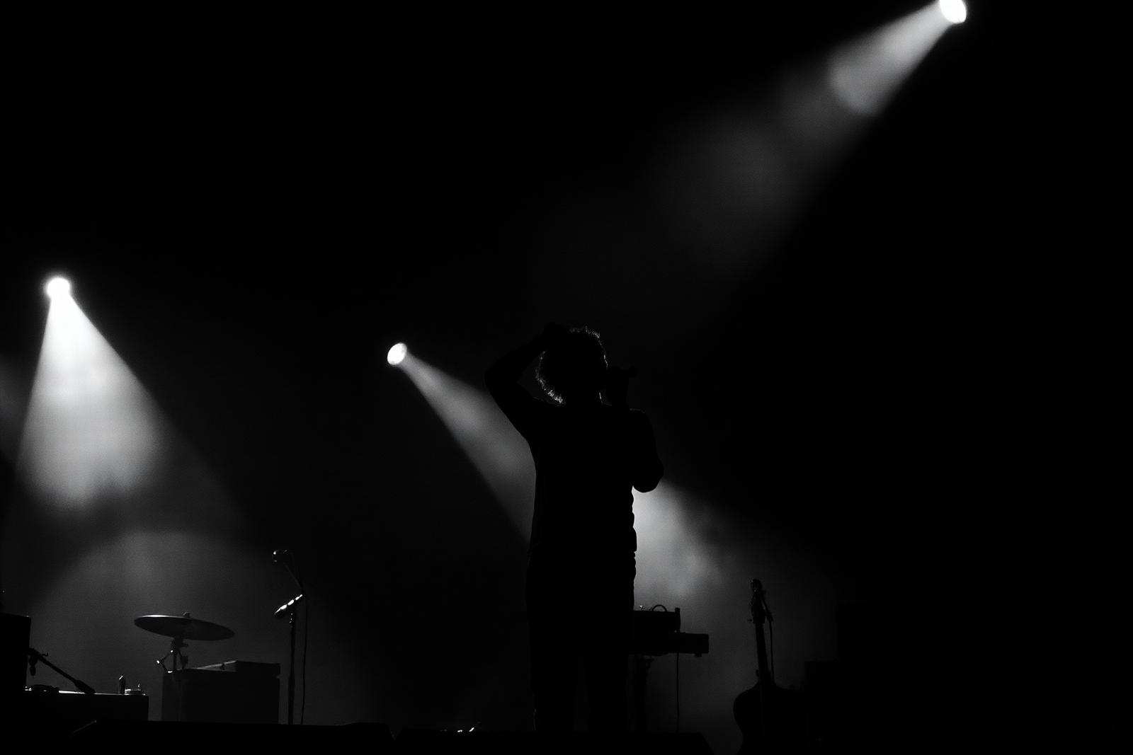 Silhouette d'un chanteur sur scène sous un projecteur blanc