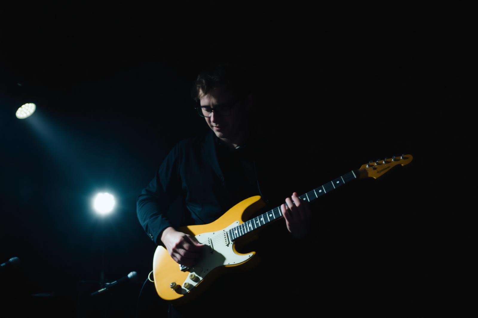 Guitariste en pleine performance dans une salle sombre